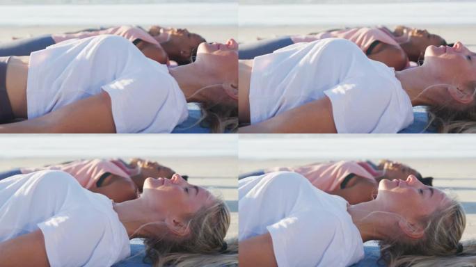 一群练习瑜伽的女性朋友，躺在沙滩上的垫子上