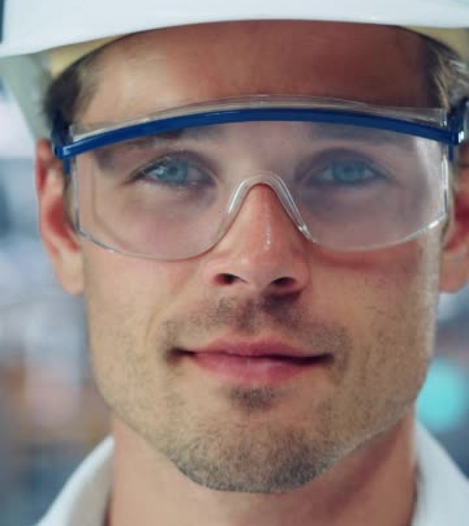 在汽车装配厂的办公室里，年轻英俊自信的工程师戴着安全镜和白色安全帽的垂直肖像。在现代工厂从事车辆生产
