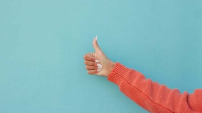 在蓝色工作室背景模型上竖起大拇指，拇指或女人的手。成功，成功或象征或女孩的认可，鼓励和动力或目标，确