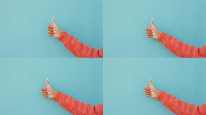 在蓝色工作室背景模型上竖起大拇指，拇指或女人的手。成功，成功或象征或女孩的认可，鼓励和动力或目标，确