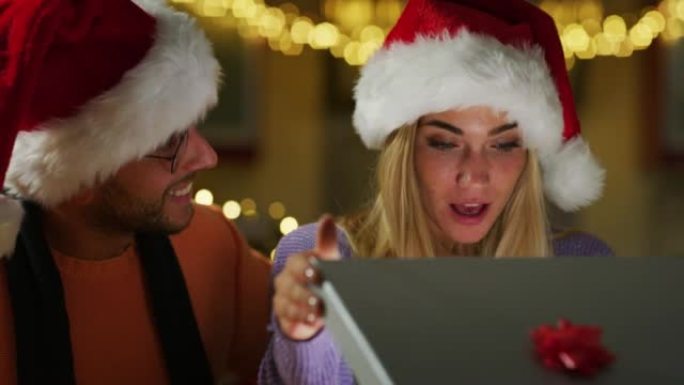 真实的快乐男人镜头正在给他心爱的女人做圣诞礼物。这位女士在打开收到的礼盒后感到惊讶和兴奋。假期、浪漫