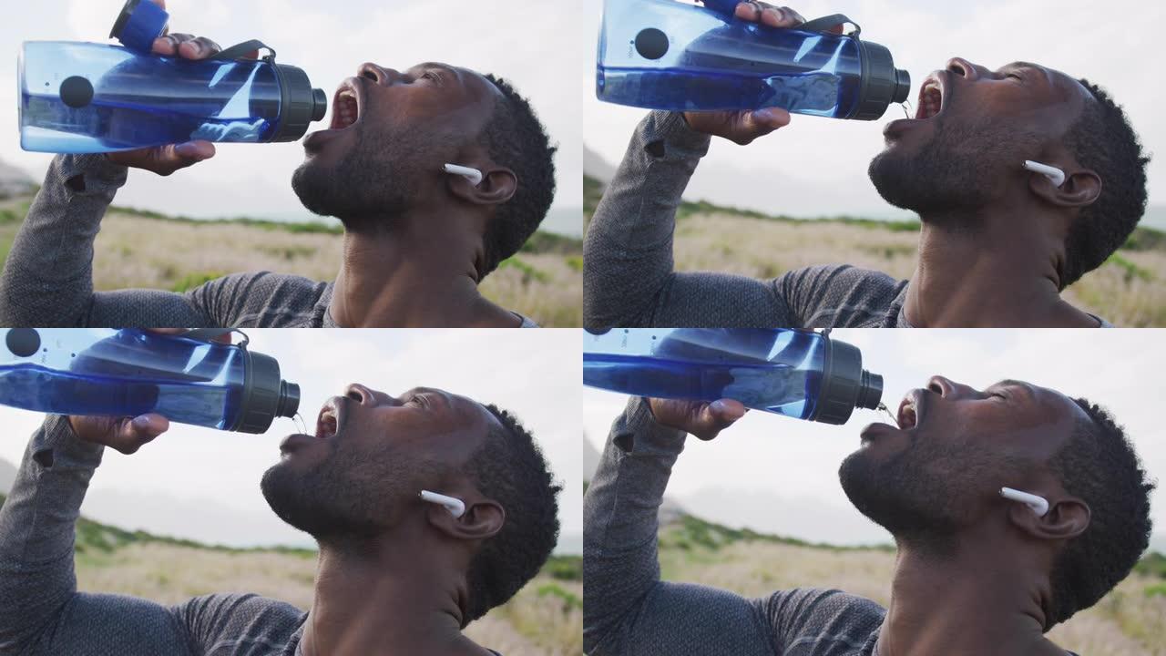 非裔美国人在山上徒步旅行时从瓶子里喝水