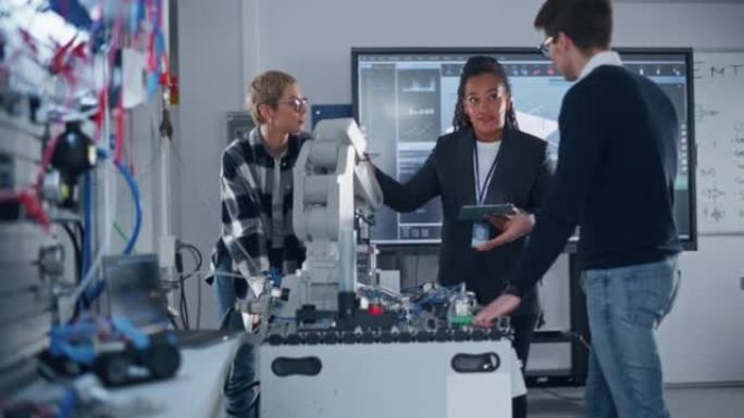 在机器人技术发展实验室: 女老师和两名学生使用机器人原型手。学生女孩笑着说些什么，和她的团队集思广益