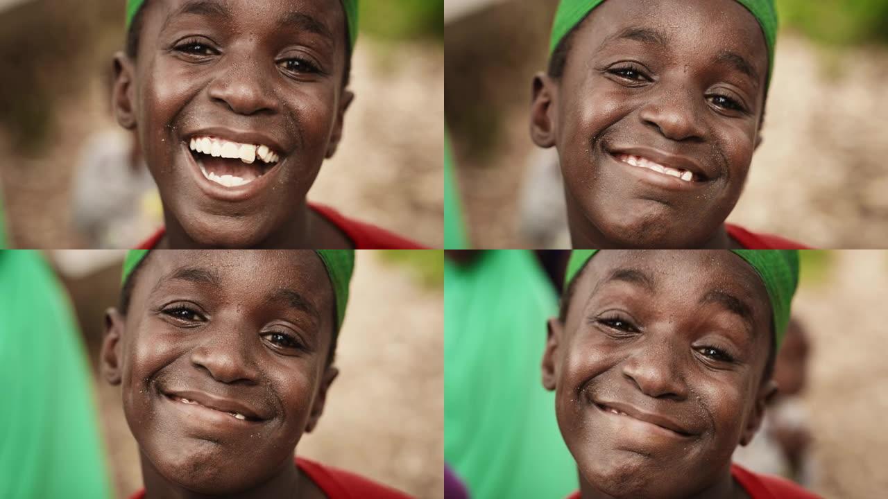 特写一个富有表现力的真实的非洲孩子微笑，眨眼，看着相机模糊的背景。快乐精力充沛的黑人男孩充满生活做滑