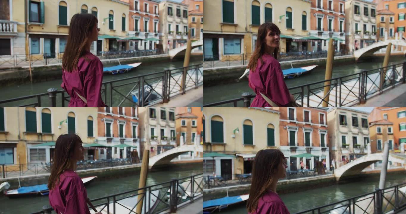 镜头跟随年轻快乐迷人的高加索女性游客沿着夏季威尼斯频道回望镜头。