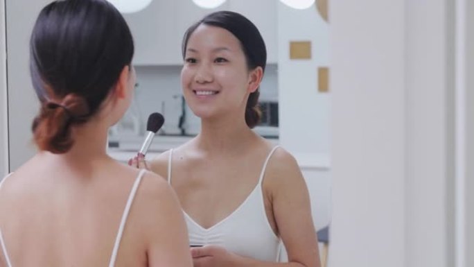 漂亮的年轻亚洲女性在镜子前化妆