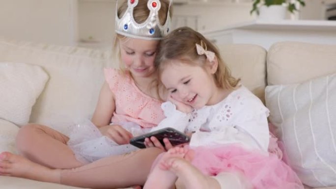 智能手机，沙发和公主儿童观看视频，游戏应用程序或在线儿童网站，用于家庭学习，节日娱乐或生日聚会。童话