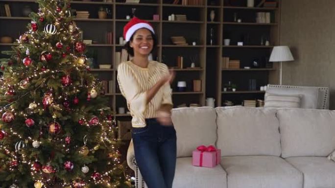 黑人千禧一代妇女在装饰好的圣诞树下在家跳舞