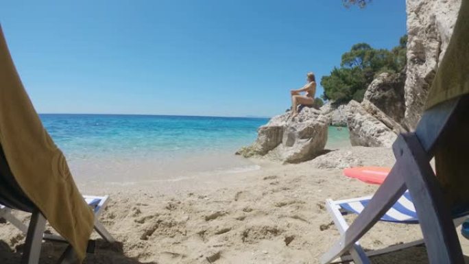 年轻女子女士在克罗地亚亚得里亚海宁静的夏日海滩上的阳光岩石上放松