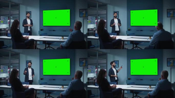 公司运营经理为一组经济学家举行会议演示。成年男性使用带有水平绿屏模拟显示的宽电视机。人们在商务办公室