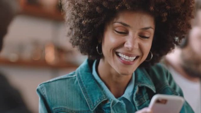 美丽的女人与非洲在咖啡馆与朋友聊天，展示智能手机社交媒体信息最好的朋友在外面分享八卦享受联系
