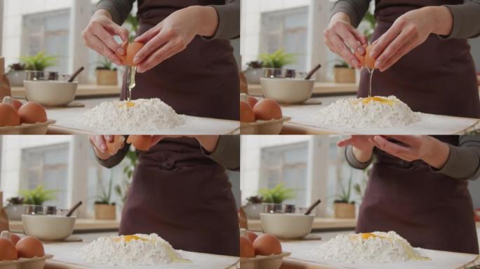 女人在厨房餐桌上向面粉中添加鸡蛋