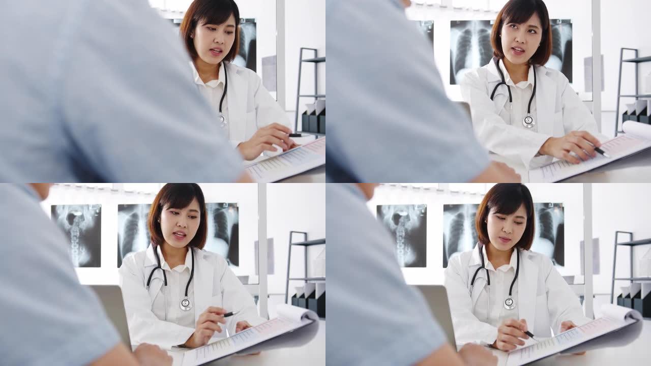 年轻的亚洲女性医生使用剪贴板正在发表重大新闻谈话，讨论结果或症状与男性患者坐在健康诊所的桌子上。