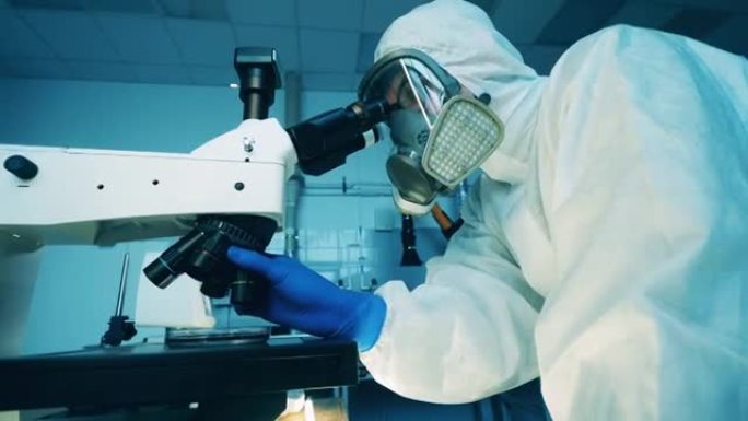 穿着防溅服的专家正在实验室里用显微镜工作