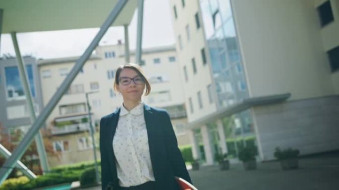 女商人在现代建筑旁边行走时拿着文件和滑板