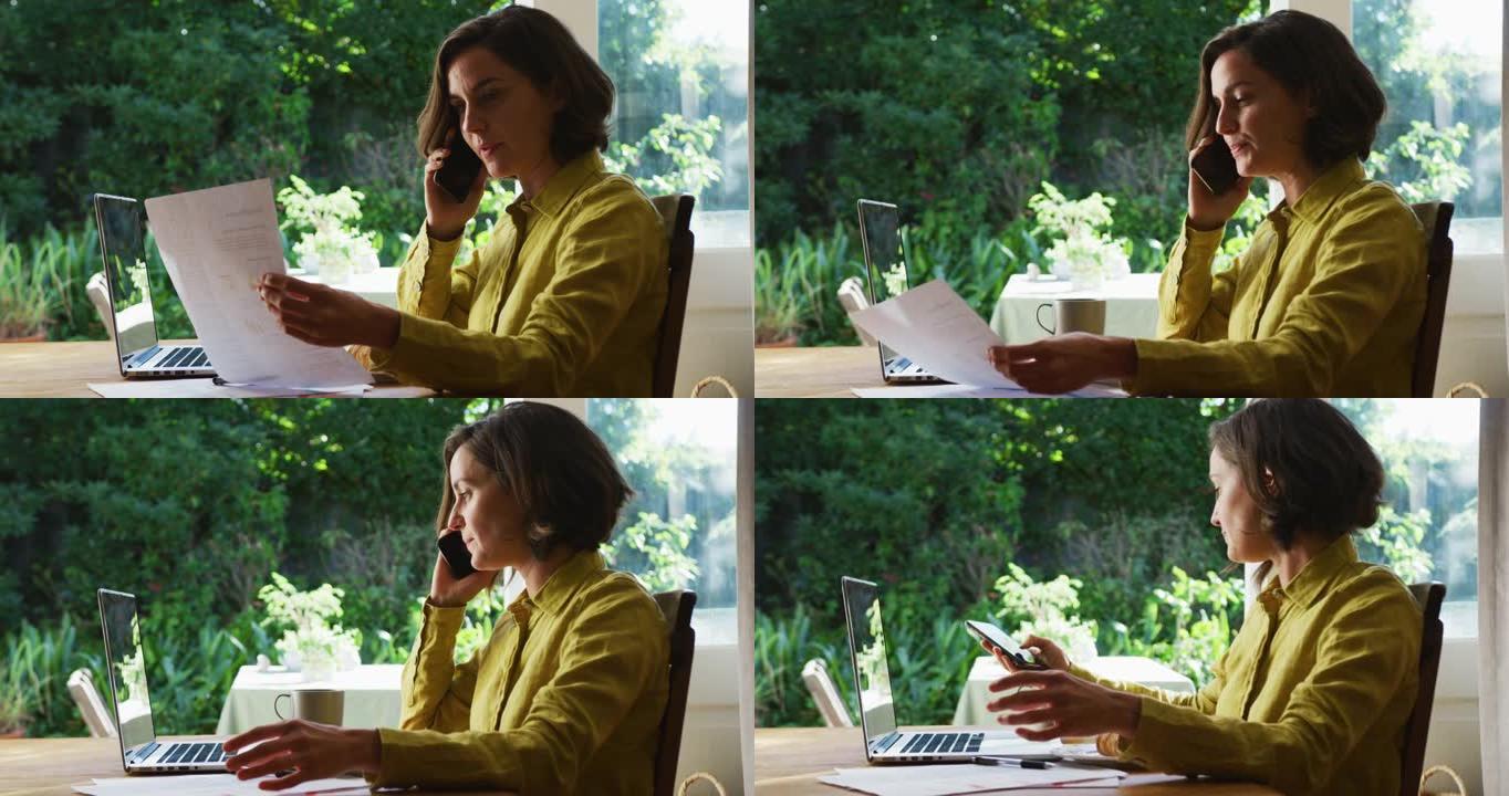 白人妇女的中段使用在家工作的笔记本电脑在智能手机上聊天