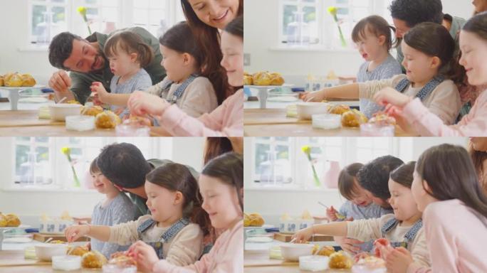 唐氏综合症女儿的家庭在家里坐在桌子旁烘烤和装饰蛋糕