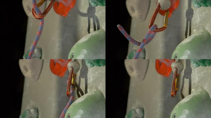 宏观: 五颜六色的贝莱绳从登山扣中滑出并沿着墙壁掉落
