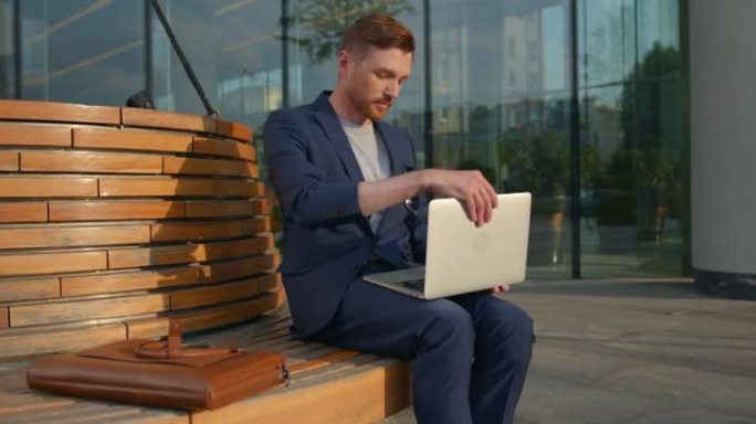 一位穿着蓝色西装的年轻迷人商人从皮革笔记本电脑包中取出了笔记本电脑