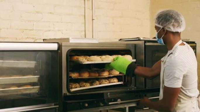 4k视频片段，一名年轻的男性面包师从面包店的烤箱中取出羊角面包