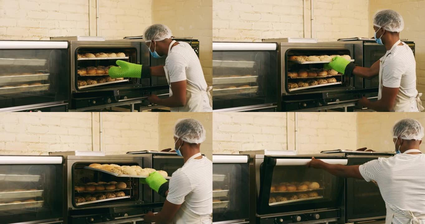 4k视频片段，一名年轻的男性面包师从面包店的烤箱中取出羊角面包
