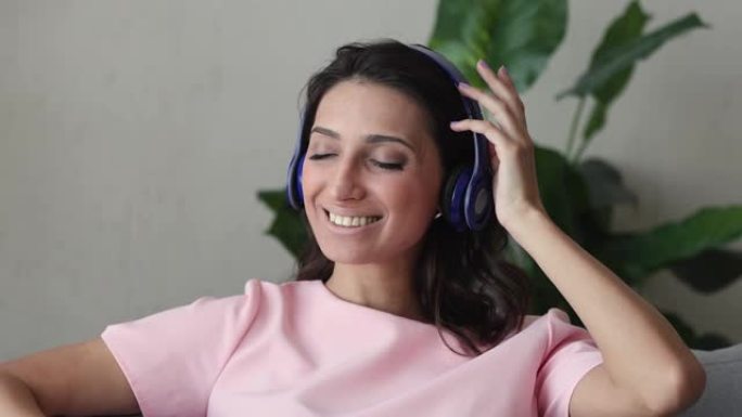印度女人在沙发上放松戴着耳机听音乐