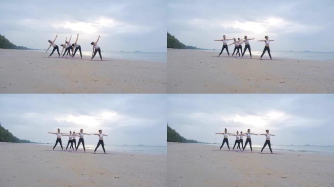 五人小组体育课在海滩上的日出早晨一起练习瑜伽课。积极的生活方式概念。