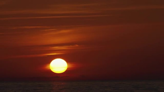 延时日落天空和美丽的海洋背景。橙色的阳光天空在反射的海洋画面上。夏日红日海景。自旋漂移云层中的大太阳