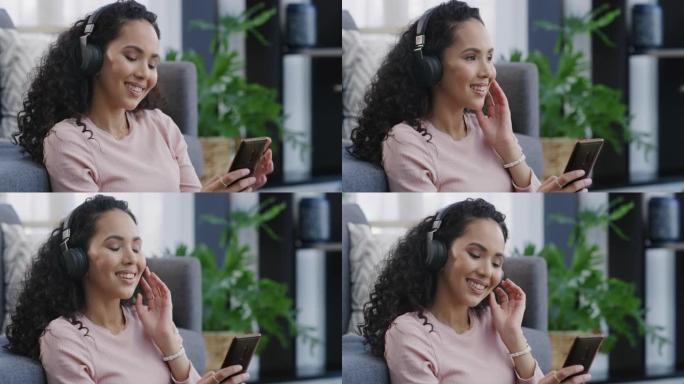 4k视频片段，一个迷人的年轻女子坐在客厅里，戴着耳机使用手机