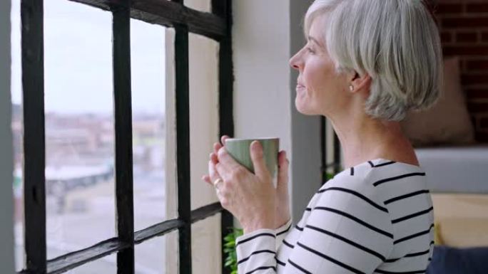 高级女性，在家中常饮咖啡并在窗户旁思考，以进行早晨的例行活动，在家里平静和放松幸福的反思。老年人，和