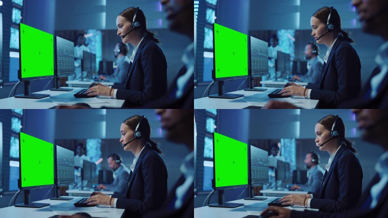 充满自信的技术客户支持专家在充满同事和显示屏的监控室中，在带有绿屏模型的计算机上工作时，可以拨打耳机