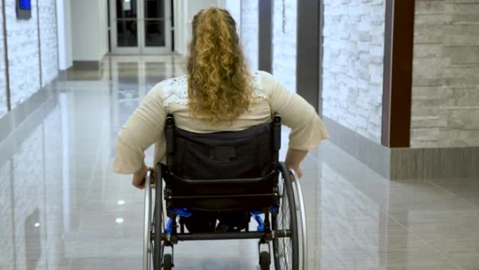 妇女在建筑物走廊上的自行式轮椅上