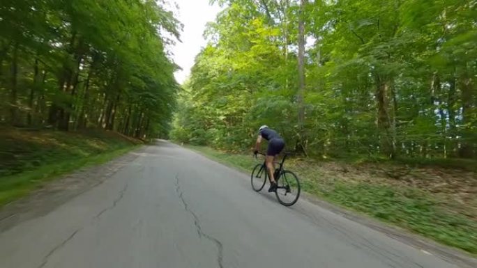晴天，空中休闲骑自行车的人骑着自行车穿过森林上山