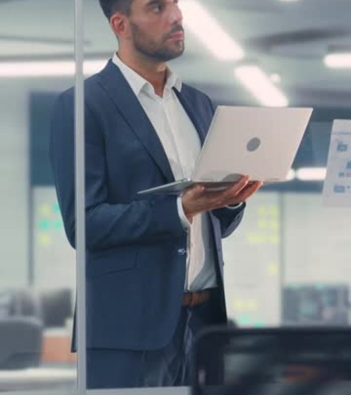 一个自信的商人在现代办公室使用笔记本电脑的垂直肖像。从事商业、金融和营销项目的时尚经理。销售专家浏览