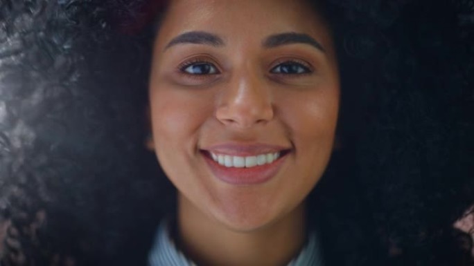 一位美丽的年轻非洲裔美国妇女的特写肖像，棕色的眼睛迷人地微笑着。快乐的年轻女子享受生活、成功和乐趣。