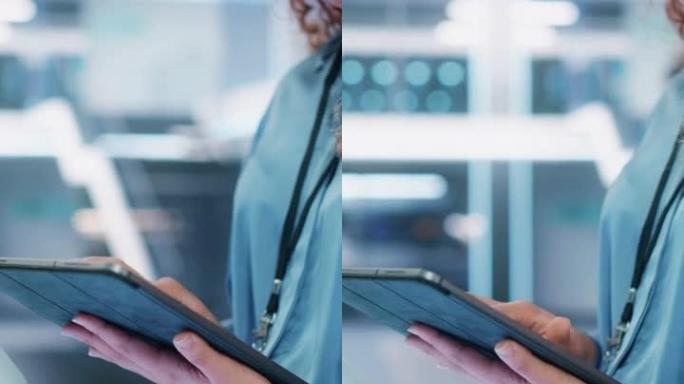 垂直屏幕: 在高科技现代工业办公设施中，女性手持和使用平板电脑的特写镜头。女人的手浏览互联网，浏览公