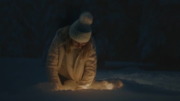 女人在雪地里挖掘并捡起发光的物体