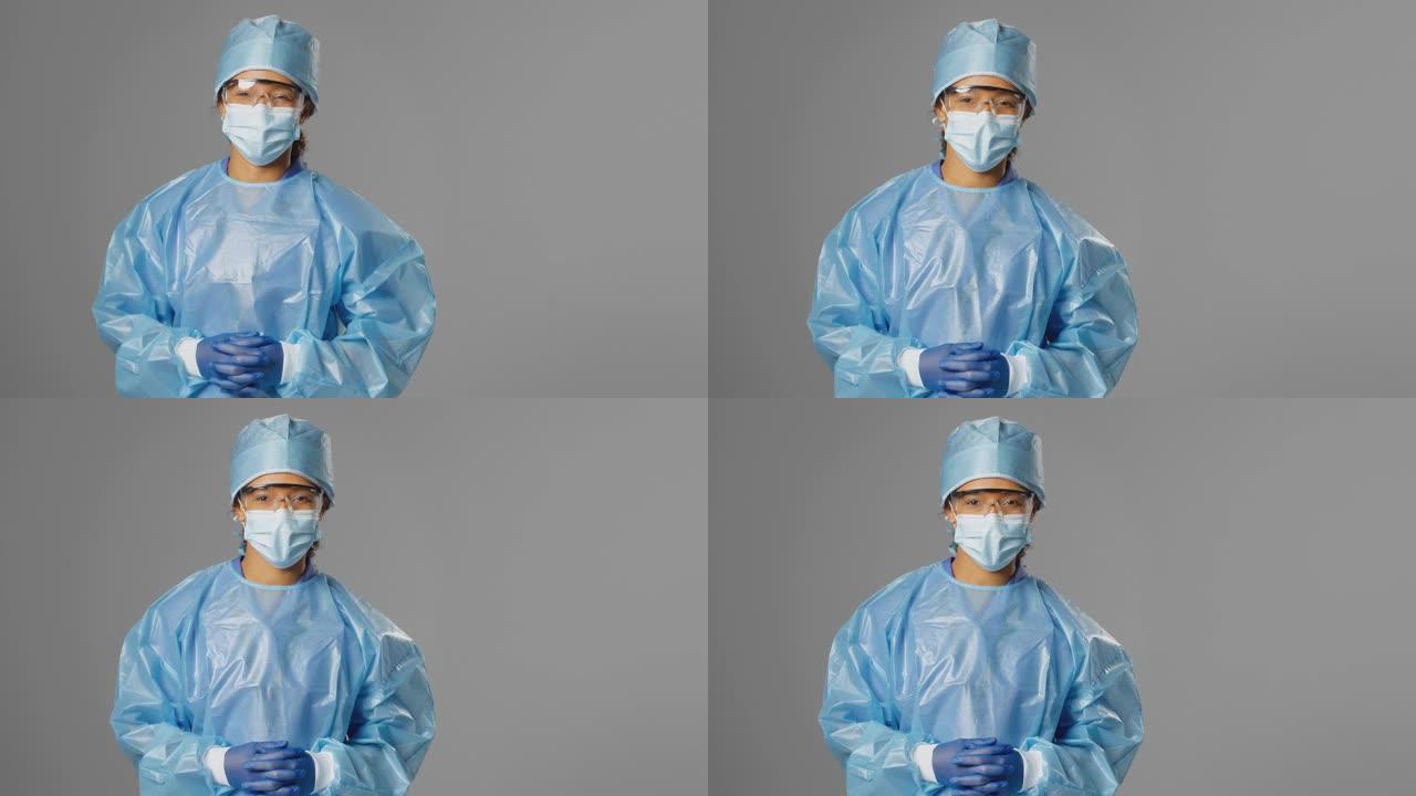 灰色背景下戴着安全眼镜和面罩的微笑女外科医生的肖像