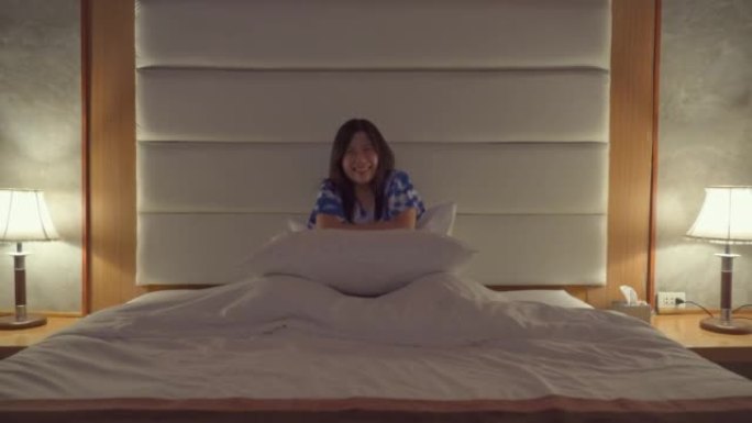 亚洲女人在电视上看喜剧电影在床上笑