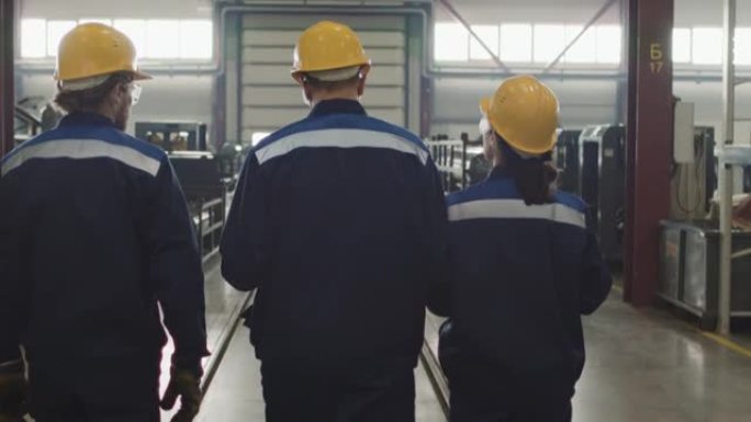 穿着工作服穿过工厂的工厂工人的后视图