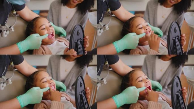 牙科医生在牙科预约时检查小女孩的牙齿和口腔。孩子对着镜子进行检查，以防止蛀牙和牙龈疾病。学习口腔卫生
