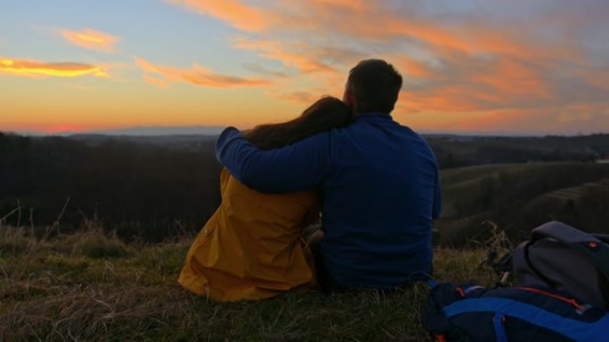 日落时浪漫的情侣在山地景观上放松