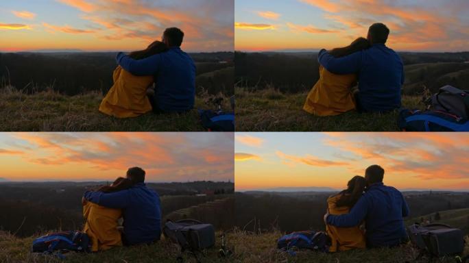 日落时浪漫的情侣在山地景观上放松