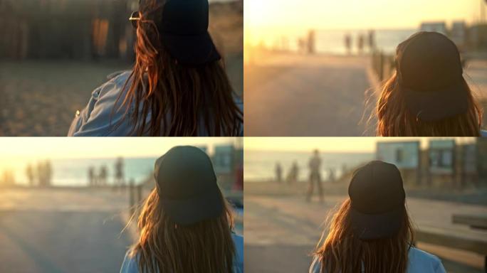 日落时，棕色头发的特写年轻女子走在海滩的木板路上，后视