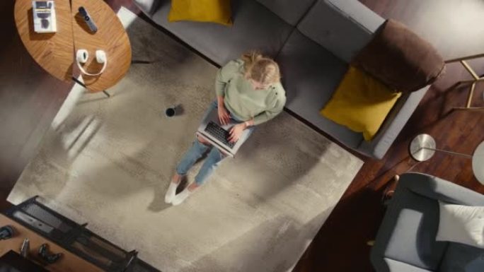 时尚的室内公寓: 年轻女子使用笔记本电脑坐在客厅的地毯上。创意自由职业者在家远程工作。做电子商务、网