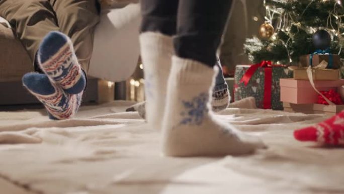 几个穿着圣诞节图案的袜子的朋友的新年派对在圣诞树旁跳舞