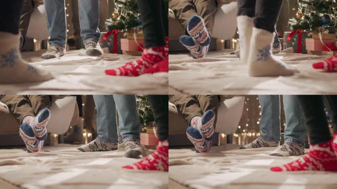 几个穿着圣诞节图案的袜子的朋友的新年派对在圣诞树旁跳舞
