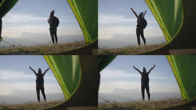 女人在山顶上徒步旅行，举手庆祝成功