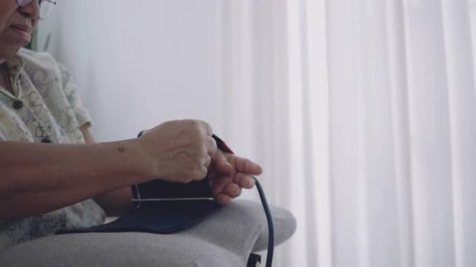 远程医疗: 在家检查血压的高级女性。