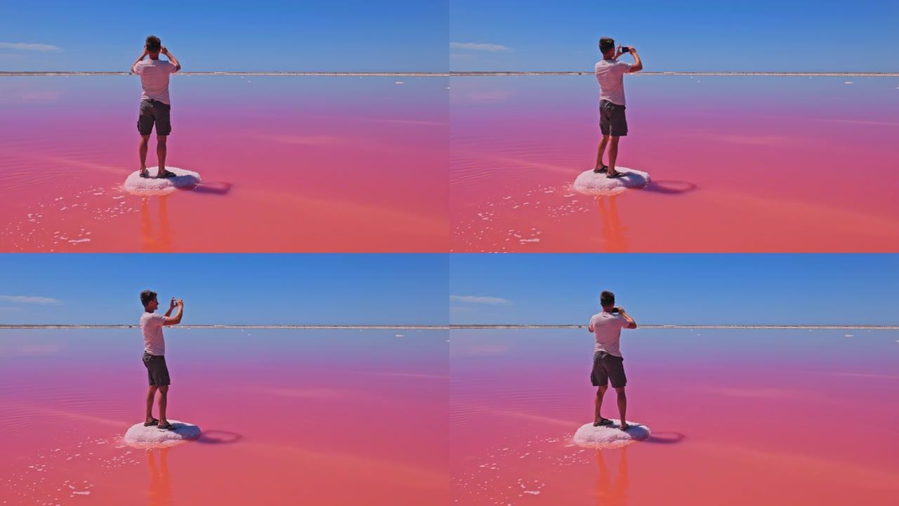男性游客用相机在盐岩上拍摄粉红盐湖